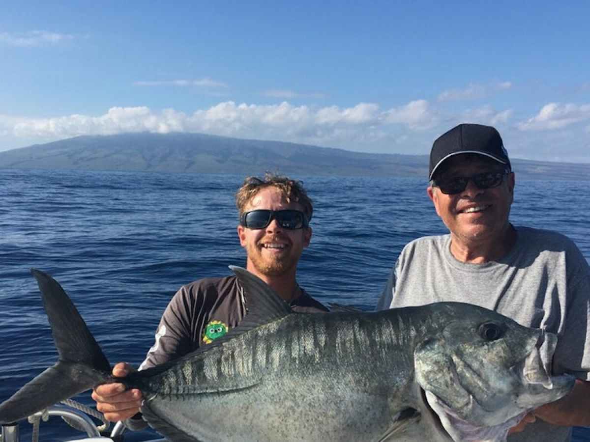 a man holding a fish on a boat in a body of water