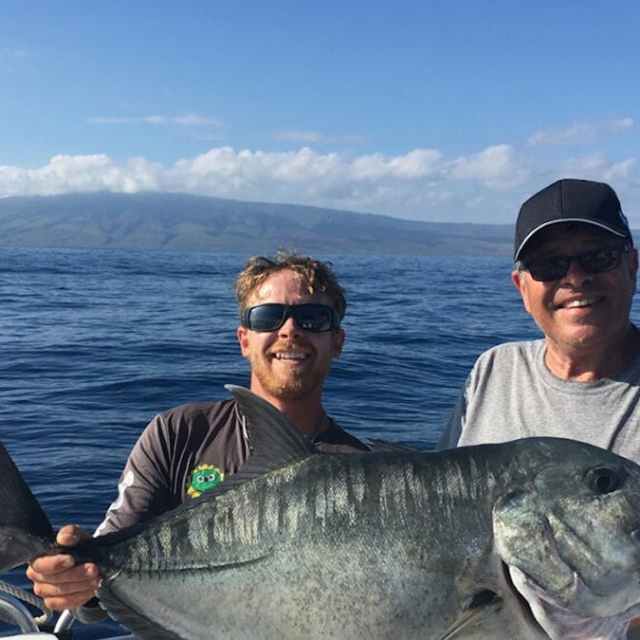 a man holding a fish on a boat in a body of water