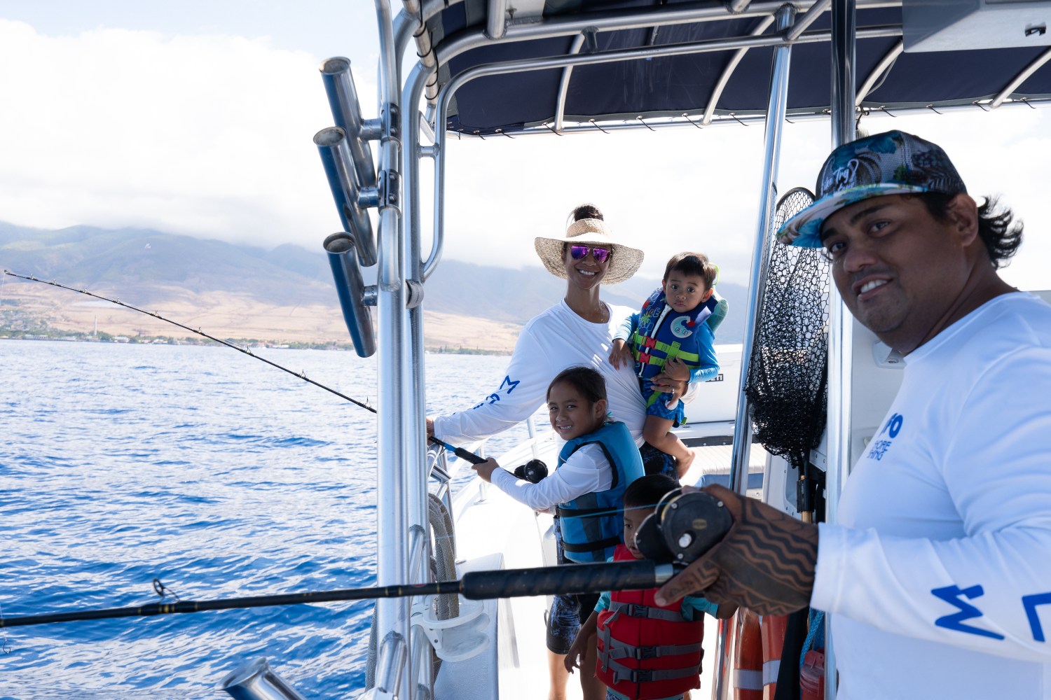 Family fishing on a boat with mountains in the background.