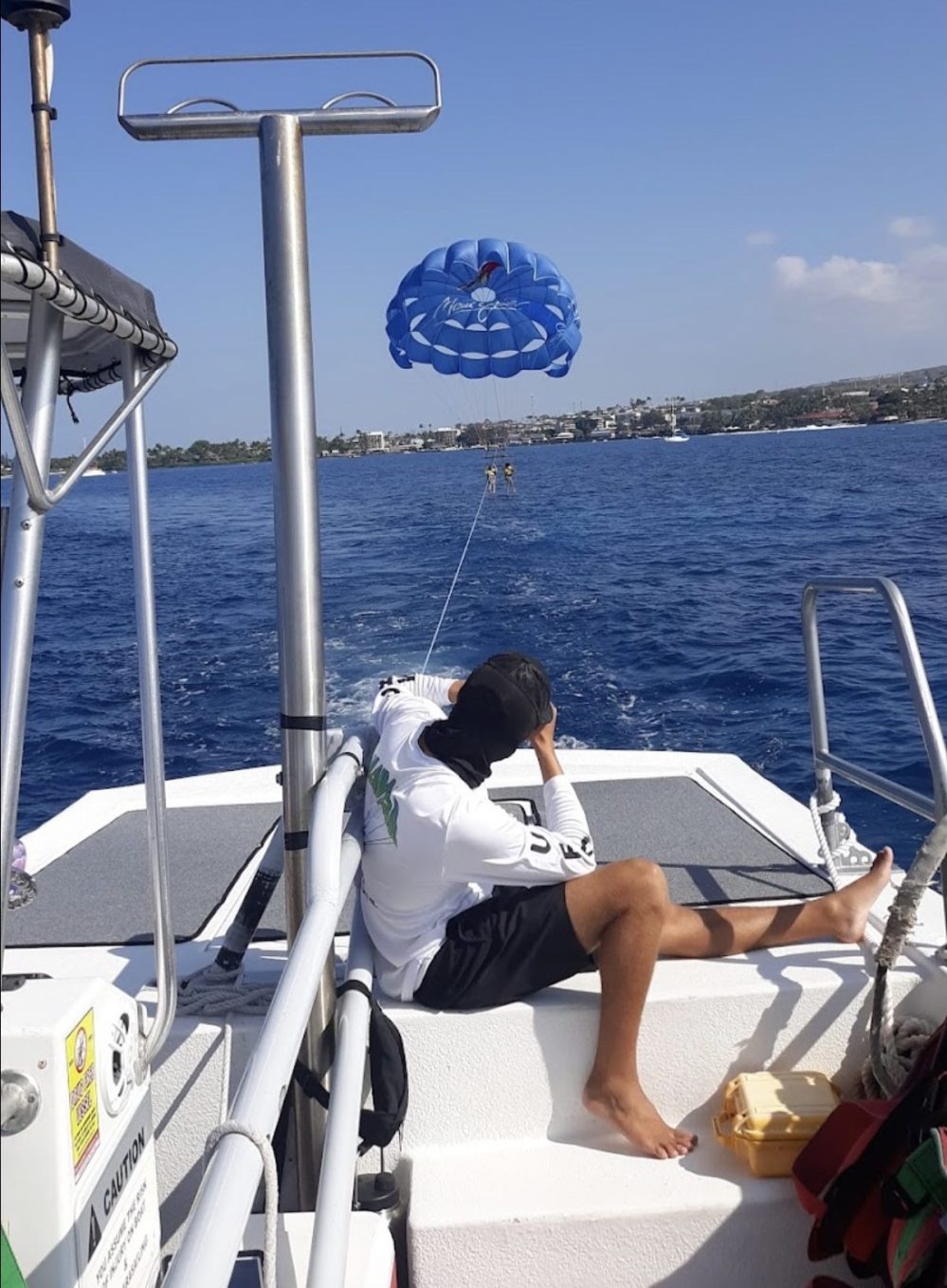 Person on boat controls blue parasail over ocean under clear sky.