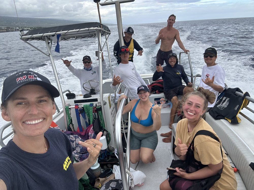 Group of people posing on a boat with the ocean in the background.